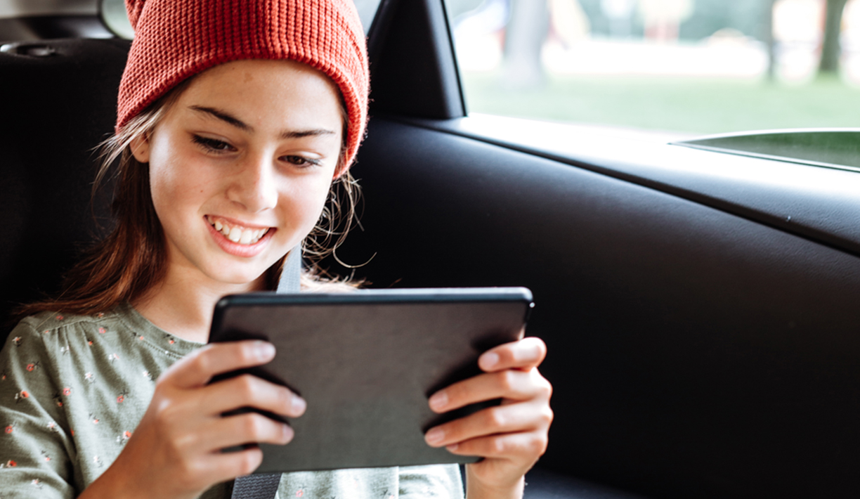 Pre-teen girl in a car with tablet